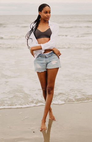 beautiful girl in braids, white shirt, jean shorts at beach