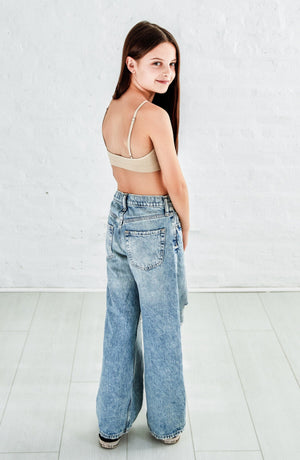 teenage girl smiling in jeans and nude color bralette