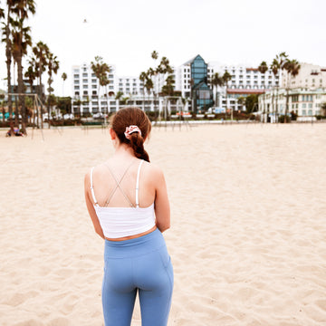 girl stanging with her back not facing the camera in a tank top and leggings