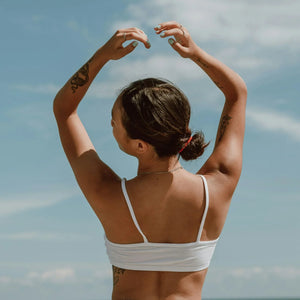 girl raising her arms up in nipple concealing bra