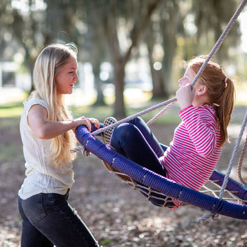 one girl pushing a tween on a swing