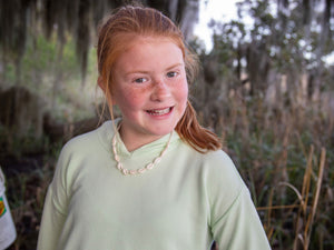 image of young girl with red smiling standing by a marsh